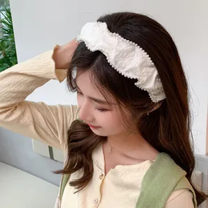 Close-up of white pleated headband with pearl edges on model for elegant styling