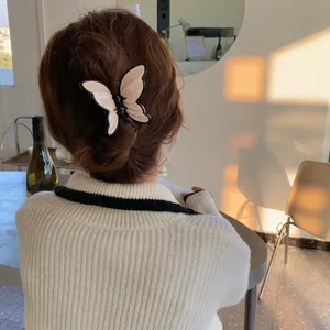 Elegant cream butterfly hair claw clip with black trim worn on long hair for women