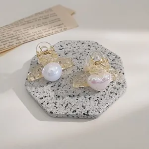 Detailed macro view of two mini hair clips with iridescent faux pearl and heart accents