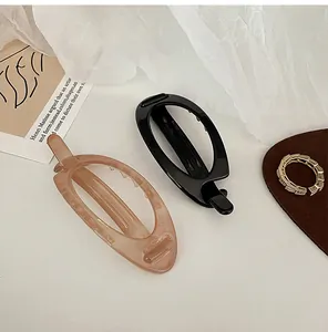 Detail of oval cutout acrylic hair clips and gold ring on aesthetic background