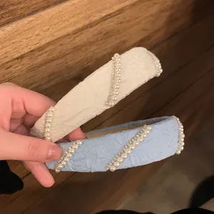 Detail of cream and light blue wide headbands with pearls and rhinestones on jacquard fabric
