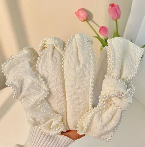 Detailed view of white fabric headbands with embossed texture and pearl embellishments