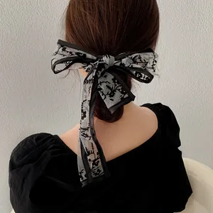 Detailed back view of vintage floral mesh bow hair scarf tied on a low ponytail