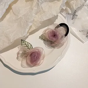 Détail de la pince et de l'élastique camélia en tulle lilas sur une assiette décorative