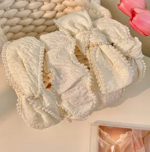 Detail of cream white pleated bow headbands with faux pearl edges in three-piece set