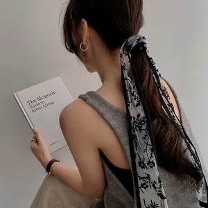 Detail of long lace hair ribbon with black floral embroidery on a low ponytail