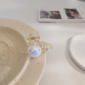 Detail of elegant faux pearl hair claw clip with iridescent finish on ceramic dish