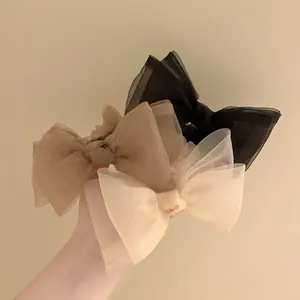 Détail de la texture des chouchous nœuds en tulle en noir, marron et beige clair