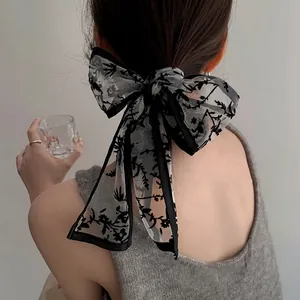 Detail of elegant black lace bow hair tie with floral embroidery and long ribbons