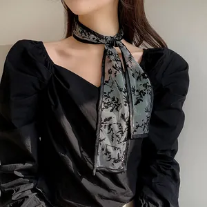 Detailed view of sheer black floral scarf styled with a V-neck puff sleeve blouse