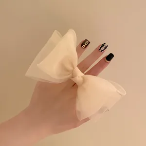 Détail d'un chouchou noeud en tulle crème montrant la texture délicate et la dimension