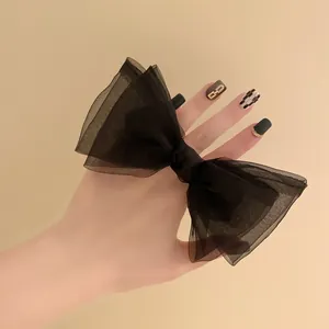 Détail d'un grand nœud en organza noir montrant les couches de maille translucide