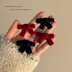 Close-up of vintage velvet bow hair clips in red and black with metallic duckbill grip