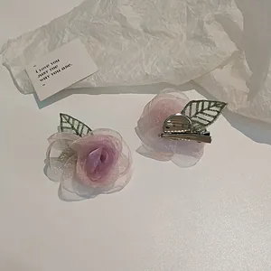 Détail de la pince camélia en tulle dégradé rose avec feuilles brodées vertes
