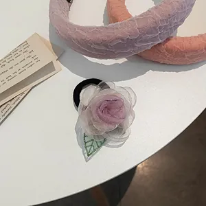 Détail d'élastique à cheveux fleur de camélia en organza lavande avec feuille verte