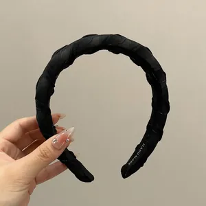Detail of handmade black fabric headband with twill texture and knot design showing label