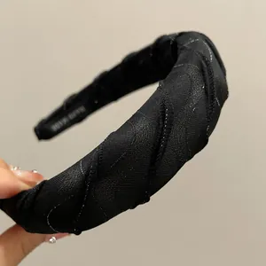 Detail of black glitter sponge headband featuring hand made label and mesh texture