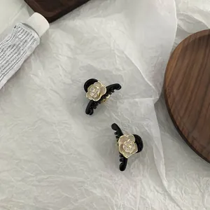 Detail shot of two mini black hair claws with white camellia flowers and pearl accents