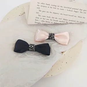 Detailed close-up of vintage satin bow hair clips with rhinestones on a ceramic plate