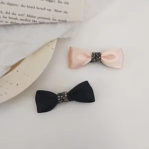Detail of pink and black satin bow hair clips with rhinestone encrusted center buckles