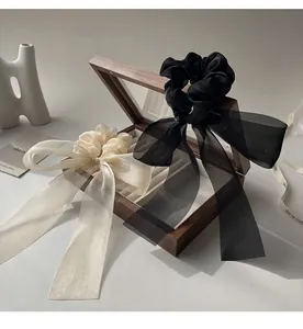 Detail of elegant black and champagne organza bow scrunchies on a wooden jewelry box