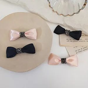 Detail view of pink and black satin bow hair clips with sparkling rhinestone centers