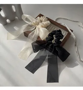 Detailed view of black and cream mesh bow scrunchies on a wooden jewelry tray