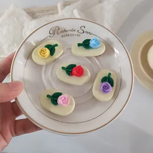 Macro detail of colorful resin 3D rose hair clips with green leaves on ceramic dish