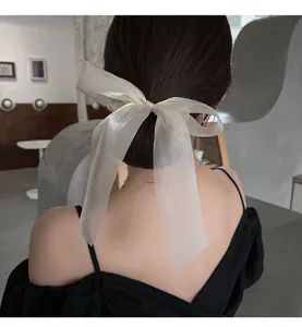 Detail of elegant cream organza bow scrunchie with long ribbons on a low ponytail