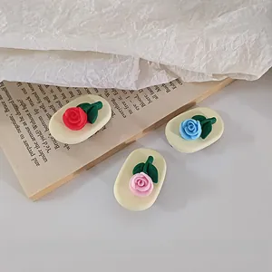 Three 3D rose hair clips in red pink and blue on a vintage book paper background
