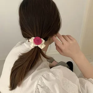 Detalle de coletero crema con sello de corazón rosa usado en una coleta alta de mujer