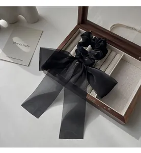 Detail of elegant black satin and organza bow hair scrunchie on a wooden jewelry box