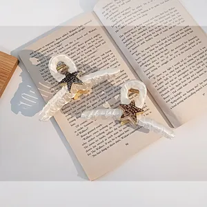 Lot de pinces à cheveux étoiles en strass blanc nacré sur fond de livre ouvert