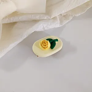 Detailed view of a yellow rose matte resin hair clip on a minimalist white background