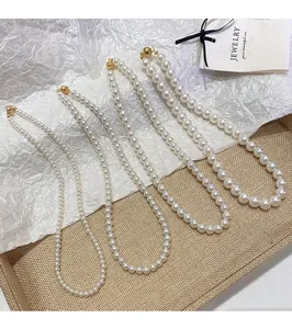 Detalle de cuatro collares de perlas de varios tamaños con cierre de bola dorada