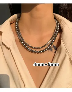 Detail van een 4mm en 8mm gepolijste metalen kralenketting gedragen als dubbele choker