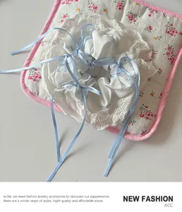 Close-up of white lace scrunchie with blue bows and cute character prints on soft fabric