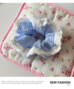 Detailed view of blue and white striped scrunchie with delicate white lace trim edge