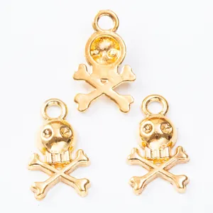 Three gold skull and crossbones metal charms for DIY jewelry making on white background
