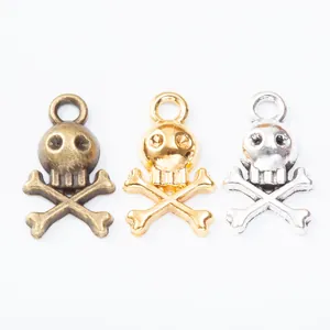 Three vintage skull and crossbones pendants in bronze, gold, and silver for DIY jewelry making