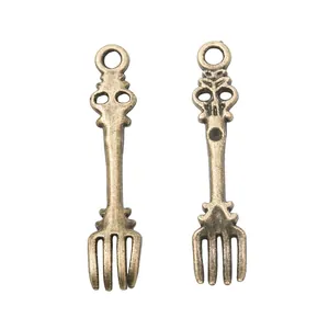 Close-up of vintage bronze spoon and fork charms for DIY jewelry making and crafts