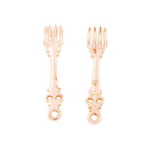 Macro shot of rose gold vintage fork charms with intricate floral engraving for DIY jewelry