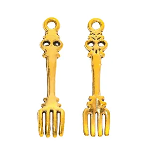 Detailed view of antique gold fork charms for DIY jewelry making on white background