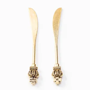 Détail de spatules vintage en alliage doré avec décor de couronne sur fond blanc