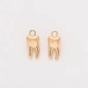 Detailed macro view of a pair of gold-finished tooth pendants with top hanging rings