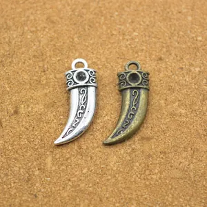 Dettaglio di ciondoli vintage a forma di corno in argento e bronzo con intagli