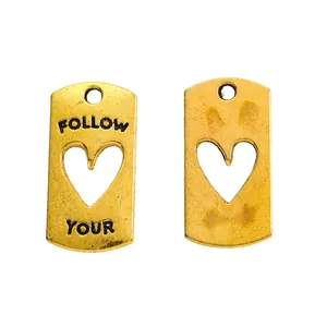 Detail von goldenen Vintage-Herzanhängern aus Legierung mit FOLLOW YOUR Aufdruck