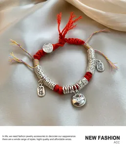 Macro-opname van de rode gevlochten armband met zilveren bedeltjes op zijde stof
