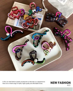 Detail of colorful resin hair claws with heart and bow designs on a wooden table