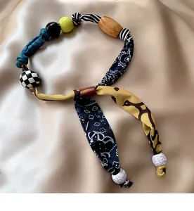 Dettaglio della collana bohémien in tessuto con sciarpa leopardata e perle artigianali
